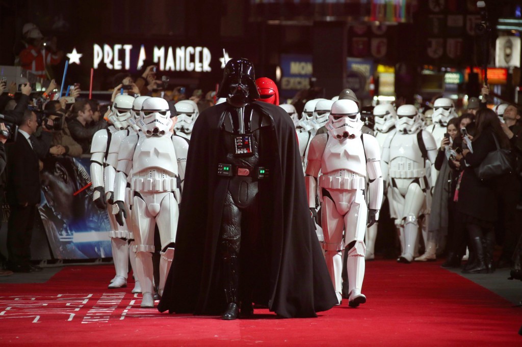 A Csillagok háborúja című filmekből ismert Darth Vader sötét nagyúrnak öltözött férfi (k) és a szintén az alkotásokban szereplő rohamosztagosok jelmezét viselő résztvevők érkeznek a Star Wars – Az ébredő Erő (Star Wars – The Force Awakens) című film nagy-britanniai premierjére Londonban 2015. december 16-án. (MTI/AP/Invision/Joel Ryan)